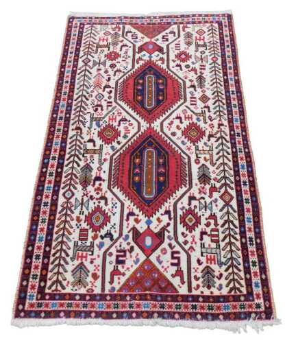 A Persian rug, with a central pole medallion, in red and navy, on a cream ground decorated with...