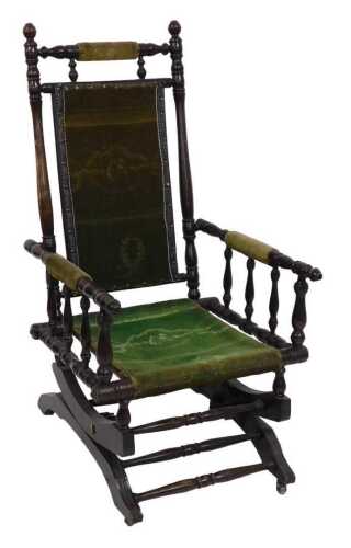An American walnut rocking chair, with carpet upholstered back, seat and armrests, with spindle...