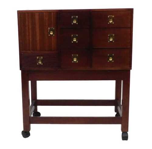 A mahogany campaign style side cabinet, with an arrangement of seven drawers and one cupboard,...