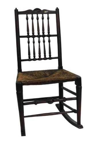 A 19thC Lancashire type ebonised ash spindle back rocking chair, with a rush seat, on turned legs.