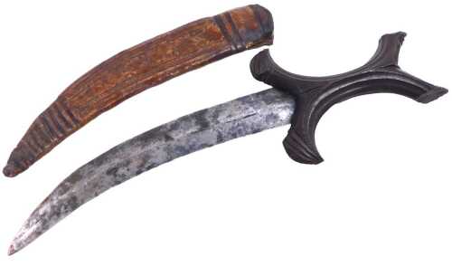 A Sudanese Beja dagger, with a curved blade and carved X form handle, in a tooled leather...