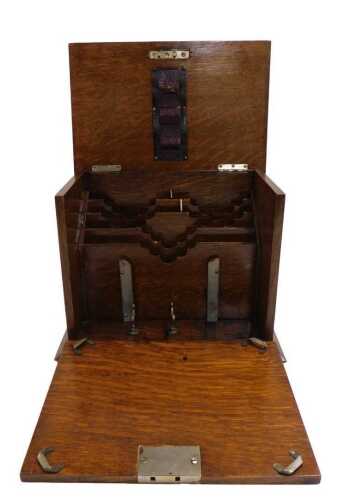An Edwardian oak stationery cabinet, the hinged lid enclosing compartments for letters, pen rack,...
