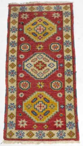 A Kazak red ground rug, decorated with three central medallions and further flowers and small...