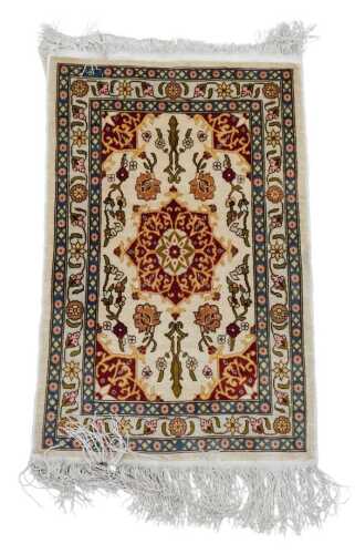 An Eastern silk Qum hanging or rug, with a central medallion, in red and gold, on a cream ground...