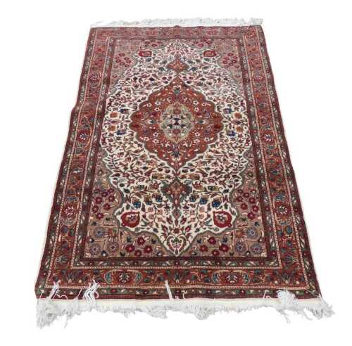 An Indian rug, with a central medallion in brown, on a cream ground decorated with leaves and...
