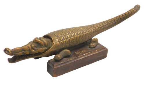A mid 20thC novelty brass crocodile nutcracker, raised on a wooden plinth, 31cm wide.