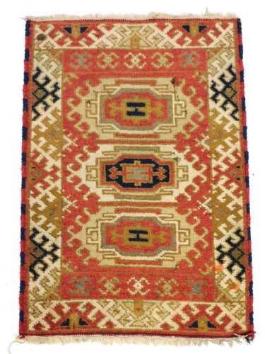 A Kazak red ground prayer rug, with three central medallions, within repeating geometric borders,...