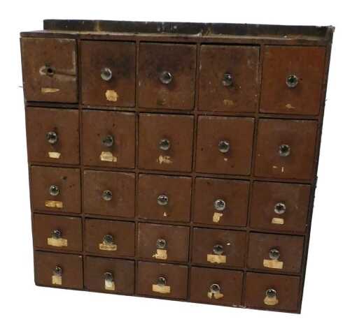 A bank of twenty-five Victorian brown painted pine show drawers, with faceted glass handles,...