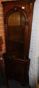 A walnut standing corner cabinet, the open top with two shelves above a door, 65cm wide.