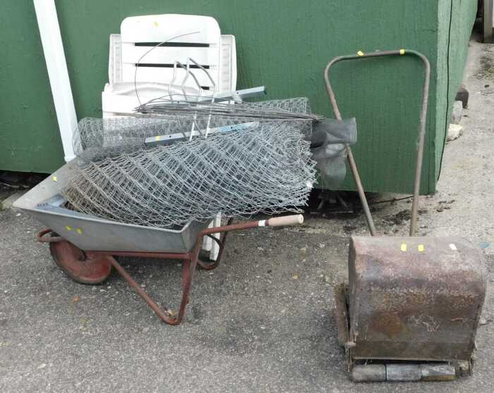 An Ironcrete wheelbarrow, with chicken wire and other wire fencing, a push lawnmower, a plastic...