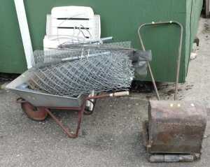 An Ironcrete wheelbarrow, with chicken wire and other wire fencing, a push lawnmower, a plastic...