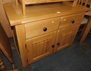 A contemporary oak sideboard, with two drawers above two panelled cupboards, raised on stiles,...