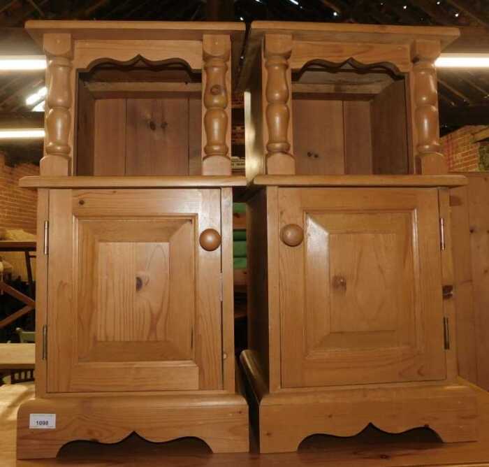 A pair of pine bedside tables, each with a recess above a panelled door, raised on bracket feet,...