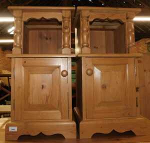 A pair of pine bedside tables, each with a recess above a panelled door, raised on bracket feet,...