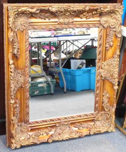 A wall mirror, in a profusely decorated surround, bevelled mirror plate, 93cm x 75cm.