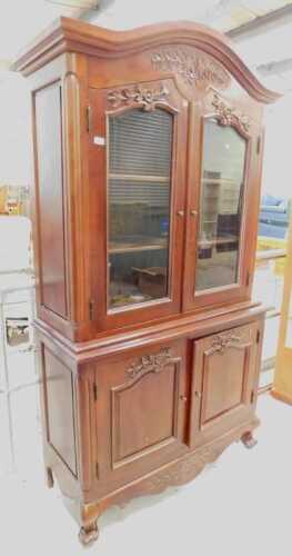 A heavily carved display cabinet, with arched top and floral frieze above two doors with raised...