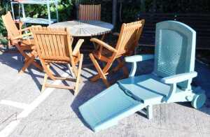 A teak harlequin patio suite, comprising table and folding chairs, with further folding recliner.