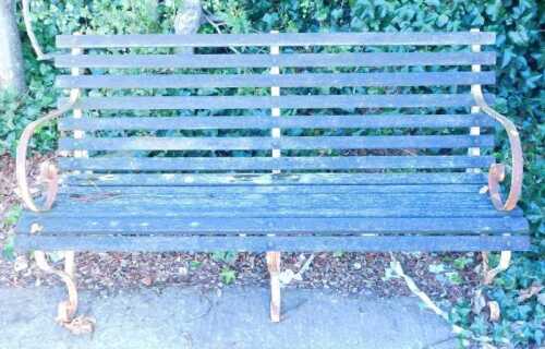 A slatted garden bench with iron scroll ends and feet.