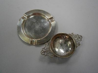 A silver ash tray and tea strainer