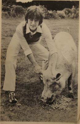 A postcard picture of John Lennon with a pig.