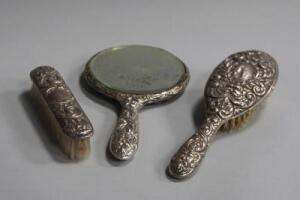 A silver backed three piece dressing table set