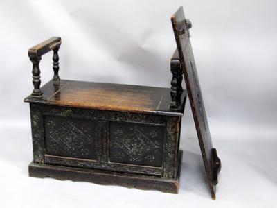 An early 20thC carved and stained oak monks bench