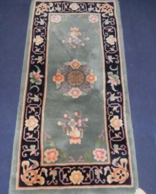 A Chinese floral green ground rug