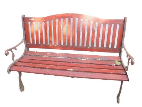 A wooden slatted garden bench with scrolling cast iron ends