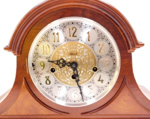 A Franz Hermle mahogany cased mantle clock, circular silvered dial bearing Arabic numerals with central foliate fret work, eight day movement, with Westminster chimes, the case of Napoleon hat form, with key, 29cm high, 46cm wide. (AF) - 6