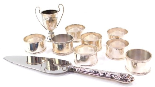 A set of six Elizabeth II silver napkin rings, by Francis Howard Ltd, Birmingham 1962, with a pair of additional napkin rings, a commemorative cup and a silver handled cake slice, 5.32oz all in.