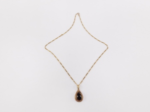 A Continental pendant, having pear cut garnet, surrounded by seed pearls, surmounted by fluted fitting, in yellow metal, with associated Italian fancy link chain marked 9ct, total length 53cm . - 2