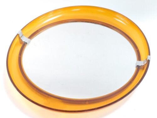 A 1970's orange acrylic framed elliptical wall mirror, inset circular glass, 50cm high, 43.5cm wide.