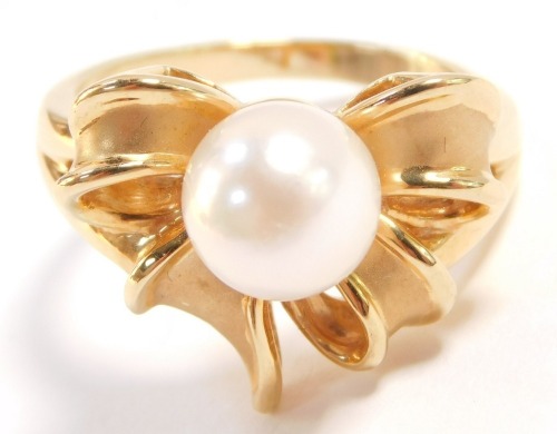 A cultured pearl ring, in a bow shaped design, set in yellow metal, stamped 18k, size K/L, pearl 7mm diameter, 5.8g.
