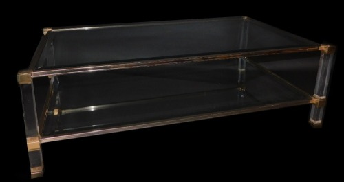 A Pierre Vandel of Paris Hollywood Regency Lucite rectangular coffee table, with bevelled glass top and under tier supported on clear perspex framing with brass finished decoration, the top 119cm x 69cm.