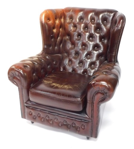 A brown leather wing back Chesterfield armchair, with buttoned decoration and studded borders. The upholstery in this lot does not comply with the 1988 (Fire & Fire Furnishing) Regulations, unless sold to a known exporter or upholsterer it will be cut fro