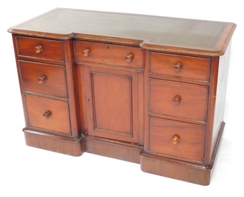 A Victorian mahogany inverted break front side cabinet, with a green leather top and a moulded edge, above an arrangement of of six drawers, each with turned wood handles around a panelled door, on a plinth, 78cm high, 121cm wide.