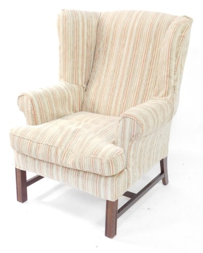 A George III style mahogany wingback armchair, with striped upholstery, on channelled legs, with H stretcher. The upholstery in this lot does not comply with the 1988 (Fire & Fire Furnishing) Regulations, unless sold to a known exporter or upholsterer it 