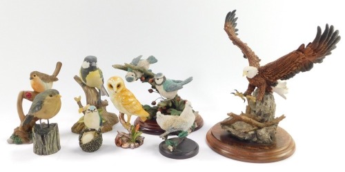 A Country Artists figure of a bald eagle landing, model CA590, 22cm high., a pair of blue tits with Hawthorne berries, model 01299, 14cm high., together with various resin and porcelain bird figures. (8)