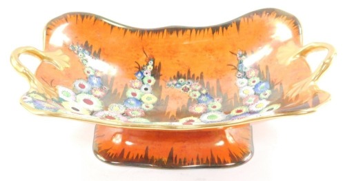 A Carlton ware fruit basket, of twin handled, footed form, decorated in the Hollyhocks pattern against an orange lustre ground, printed marks, 30cm wide.