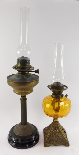 Two Victorian brass oil lamps, one with an amber glass reservoir, both with glass chimneys, 72cm high and 55cm high.