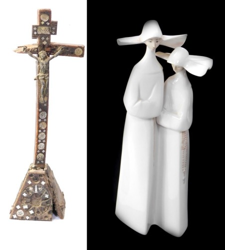 A Lladro porcelain figure of two nuns, together with an antique Continental wooden memorial cross, each 33cm high. (2)