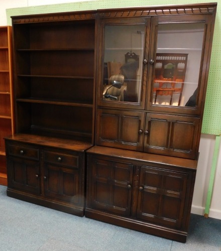 Two Ercol elm room units, each with a shaped and carved cornice, one section with shelves, two drawers and two panelled doors, another with two glazed doors, two pairs of doors on a plinth, 197cm high, 196cm overall.