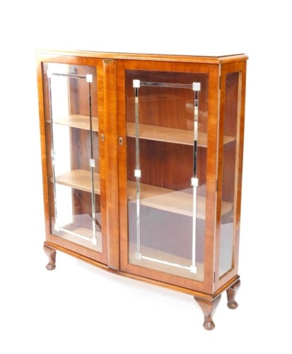 A walnut Art Deco style bow fronted display cabinet, with two glazed doors, each applied with mirrored panels, on cabriole legs with pad feet, 122cm high, 106cm wide.