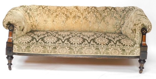 A Victorian Aesthetic movement ebonised and parcel gilt Chesterfield sofa, with a buttoned back, upholstered in green patterned fabric, the arm supports inlaid in burr walnut, on ceramic castors, 195cm wide.