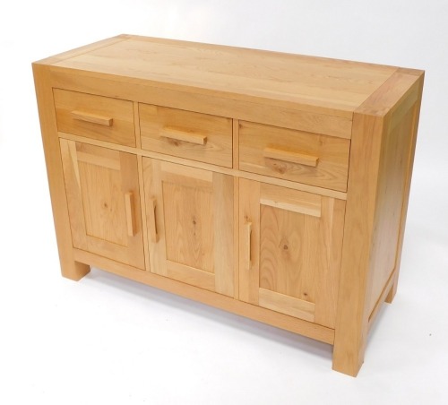 A light oak sideboard, plank top, with three frieze drawers and three paneled doors, on stiles, 87cm high, 120cm wide, 50cm deep.