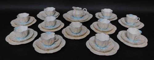 A Wileman Foley porcelain tea service, printed with a design of flowers, in blue and brown, pattern number 9035, printed and painted marks, comprising bread plate, cream jug, eleven cups and saucers and twelve tea plates.. (AF)