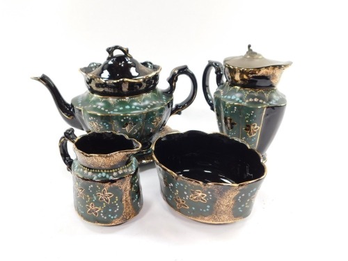 A Jackfield Pottery late 19thC part tea set, gilded and enamelled with leaves against a green and black ground, gilt heightened, comprising teapot on stand, hot water jug with hinged metal lid, cream jug and sugar bowl. Note: We have instructions from th