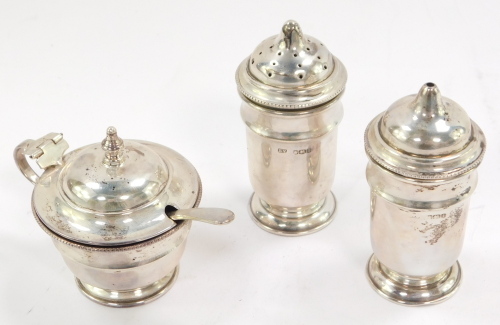 A George VI/Elizabeth II silver three piece condiment set, with a matched silver mustard spoon and blue glass liners, Sheffield 1951/1952, 4.24oz.