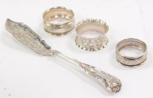 A Victorian silver King's pattern butter knife, with foliate engraved blade, Chawner & Co, London 1879, together with three silver napkin rings, with engraved foliate decoration, Chester 1904 and 1905, 3.2oz.