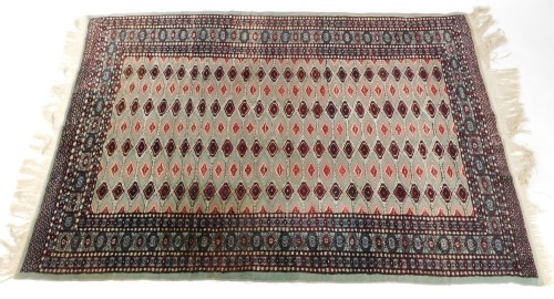 An Afghan wool and silk mixed rug, turquoise ground decorated with seven rows of repeating guls, in floral borders, 184cm x 131cm.